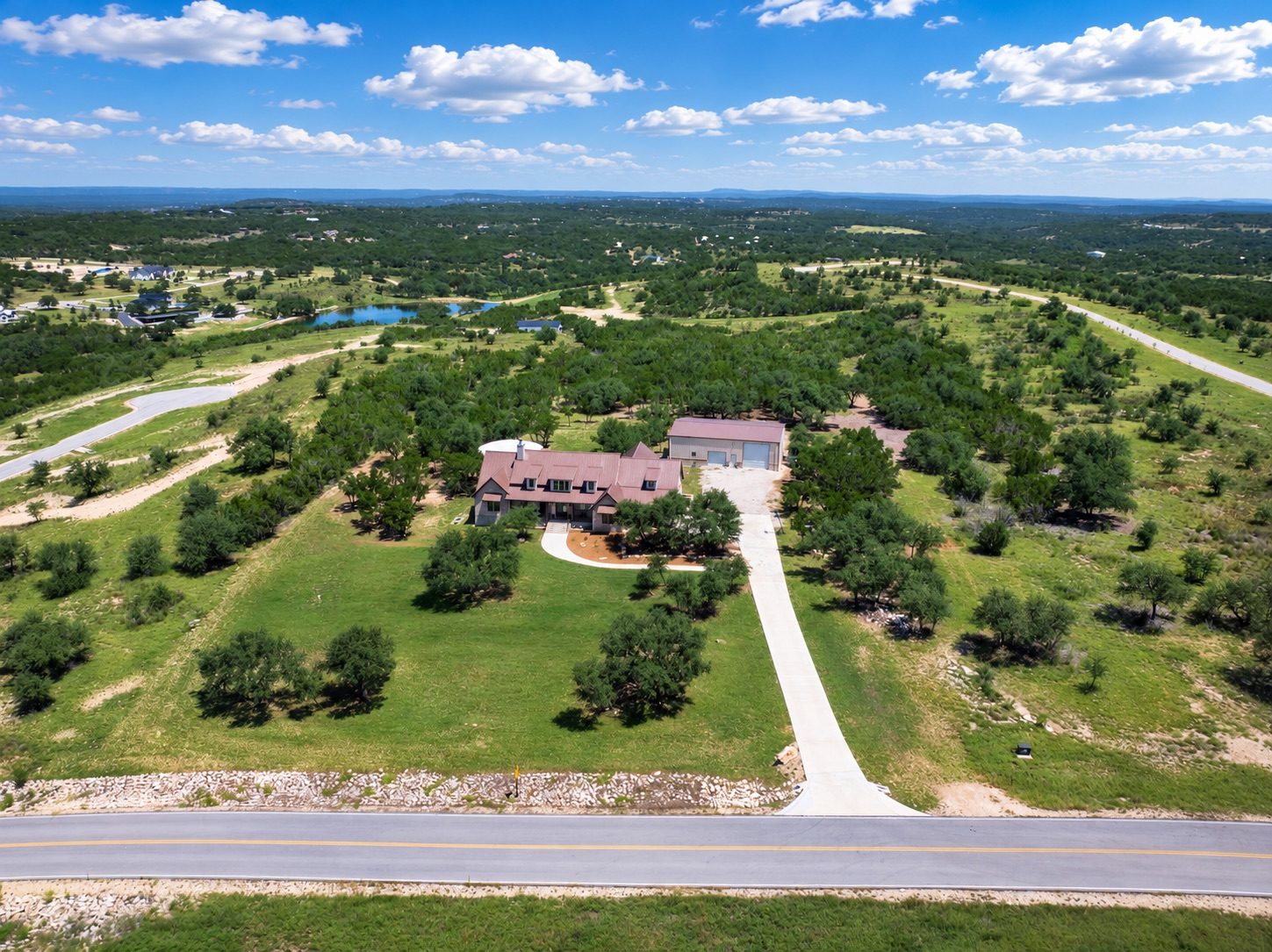 Aerial view of 1516 E Flying Owl — the home and shop on five green acres with the Hill Country beyond